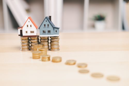 Two model houses on stacks of coins representing family assets
