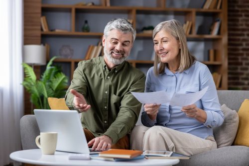 Mature couple reviewing retirement documents with a laptop at home