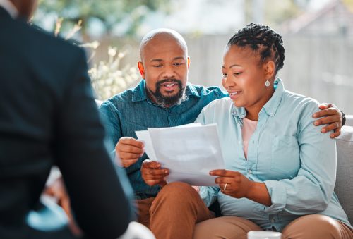 Couple reviewing documents with a financial advisor at home