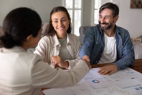 Couple shaking hands with a financial advisor over investment portfolio charts